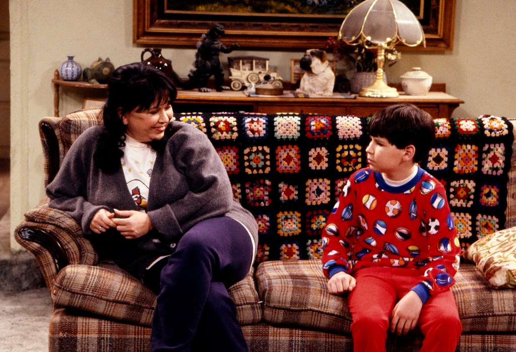 Roseanne Barr and Michael Fishman sit on a sofa in a scene from the sitcom 