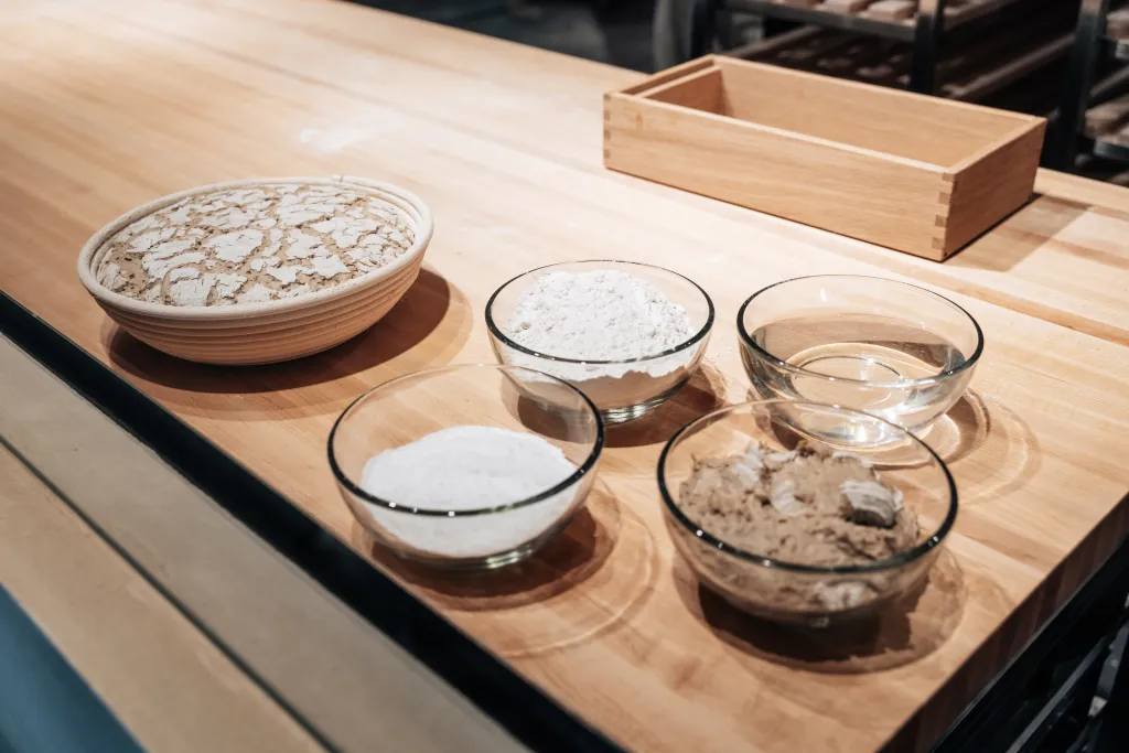 Ingredients for rye bread: flour, water, salt, yeast, and dough in a proofing basket.