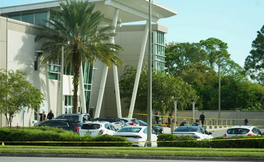 The Port Orange Police Department building with yellow police tape in the foreground and police officers on the scene.