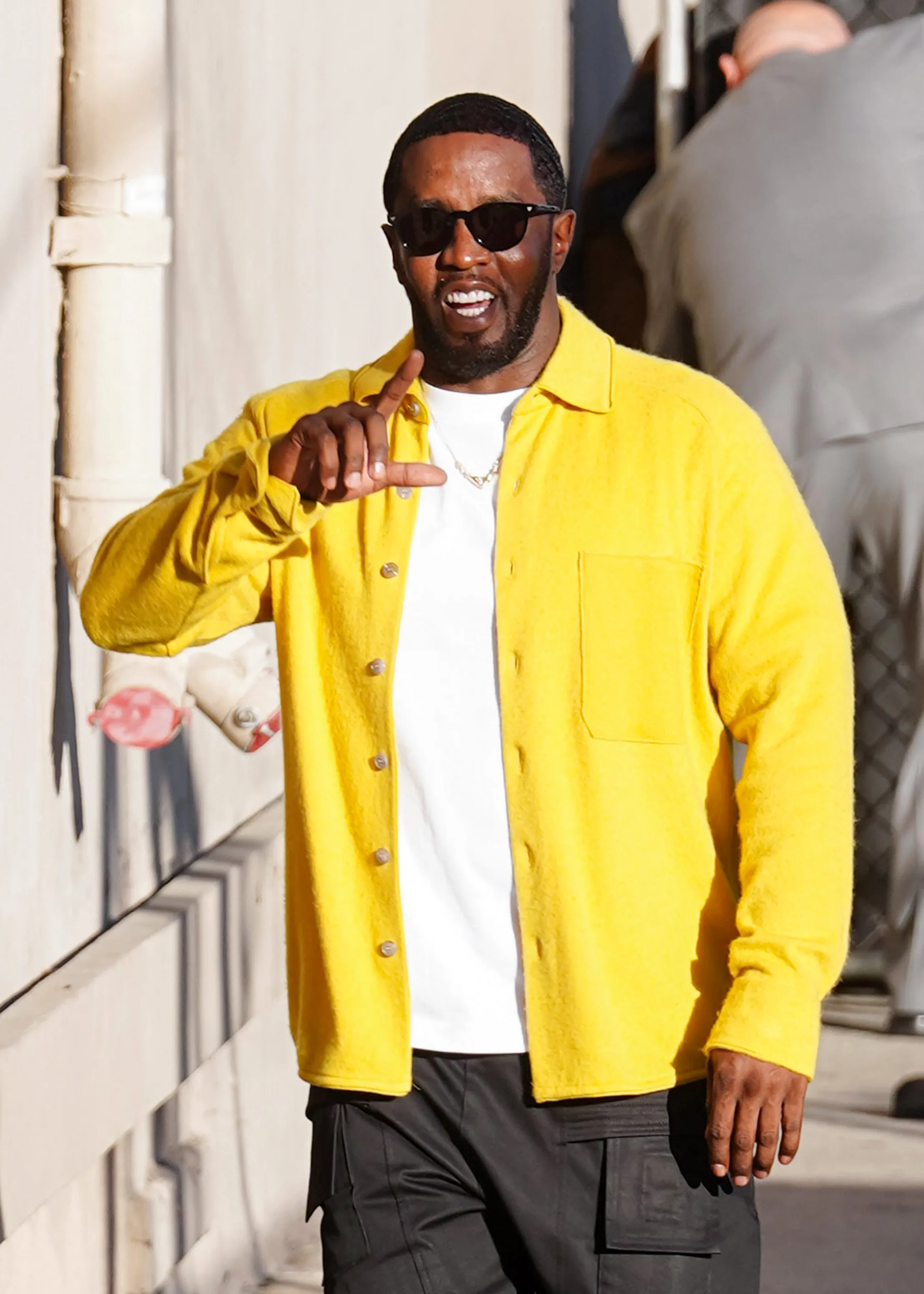 Sean Combs wearing a yellow button-down shirt and sunglasses arrives at Jimmy Kimmel Live.