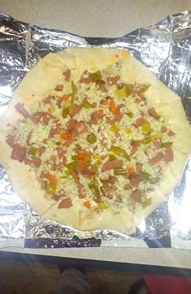 A homemade prison pizza on aluminum foil.