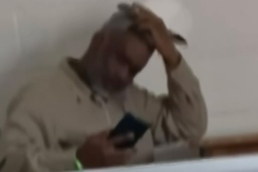 Sean Combs sitting in a correctional facility while holding a phone.