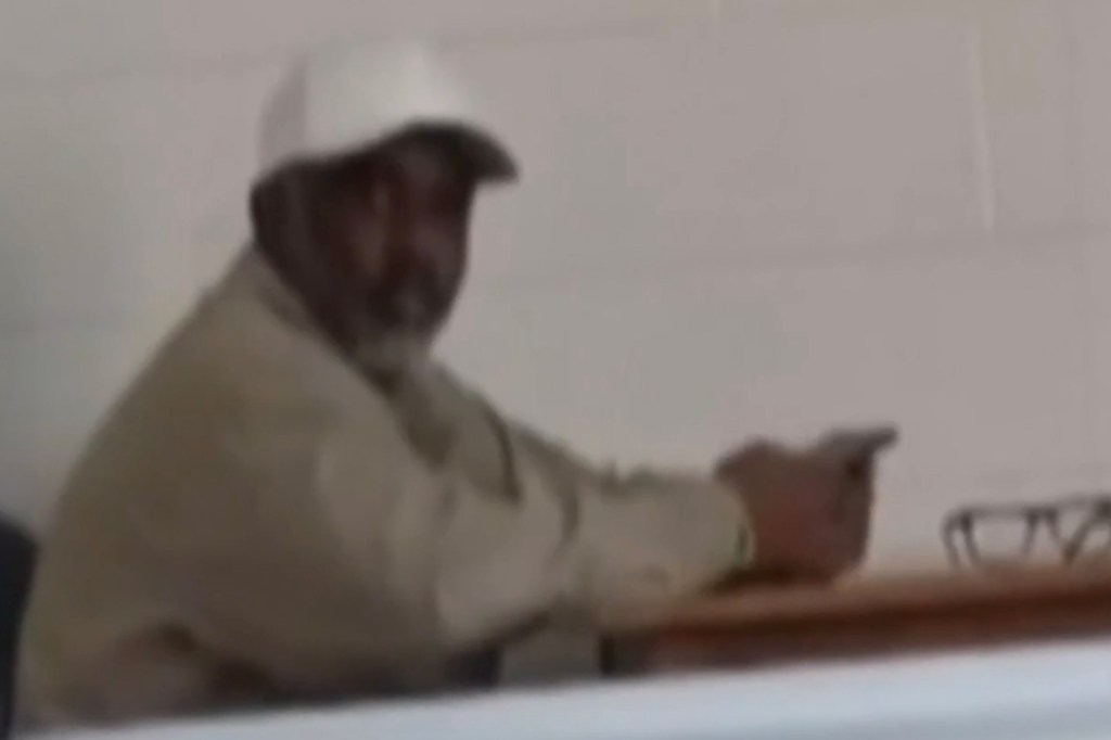 Sean Combs wearing a white baseball cap and light-colored shirt sitting at a desk.