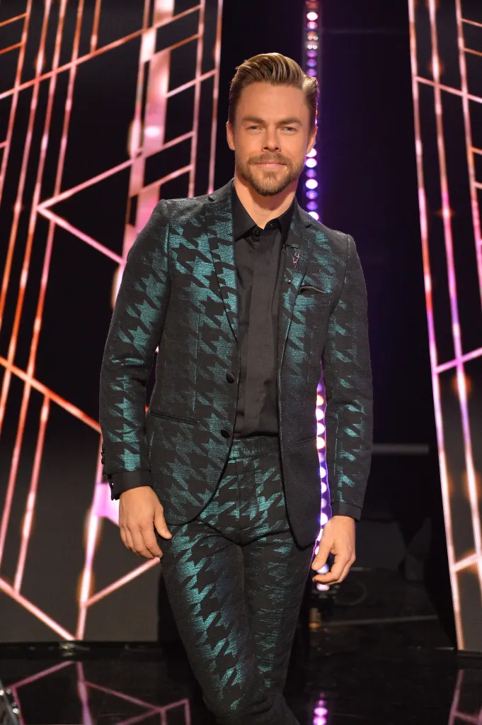 Derek Hough smiling in a teal and black houndstooth suit.