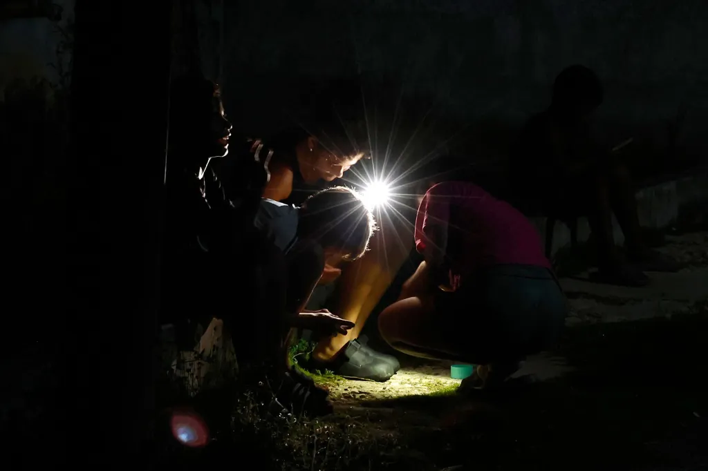 People light their path with the cell phone flashlight during a the latest blackout to hit the island nation.
