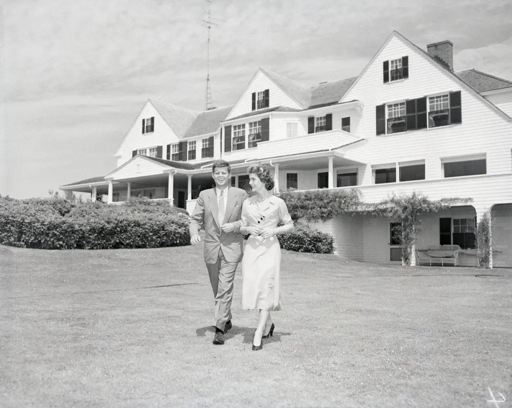 Senator John F. Kennedy and Jacqueline Bouvier stroll on the lawn of his family's home after announcing their engagement.