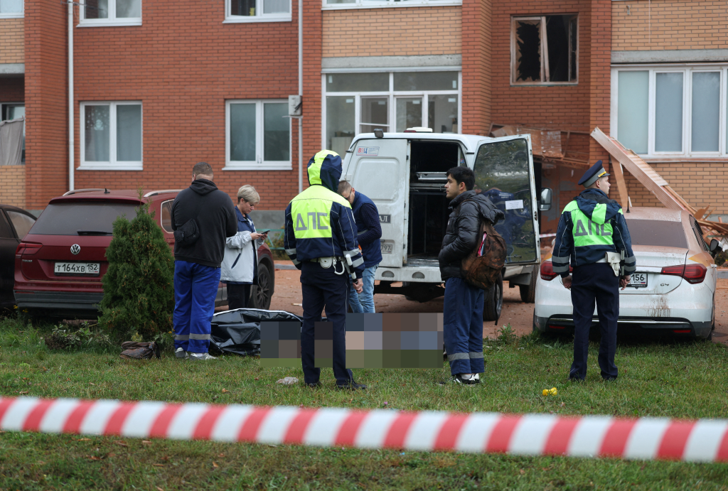 Emergency services personnel stand around the body of a victim in the Sofyino settlement in the Ramensky district of the Moscow region.