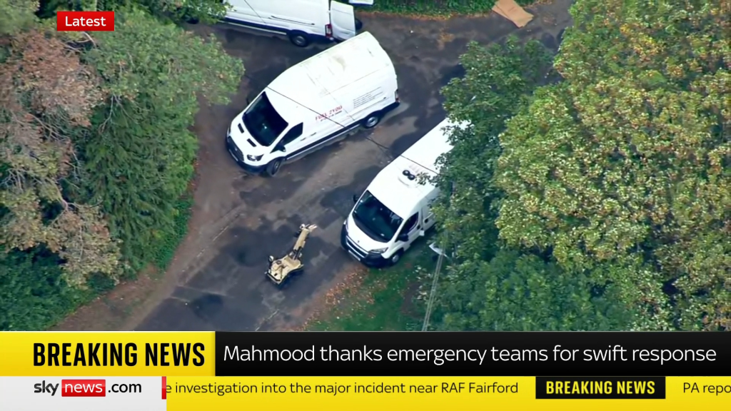 A bomb squad robot inspecting vans near RAF Fairford after arrests related to explosives and chemicals.