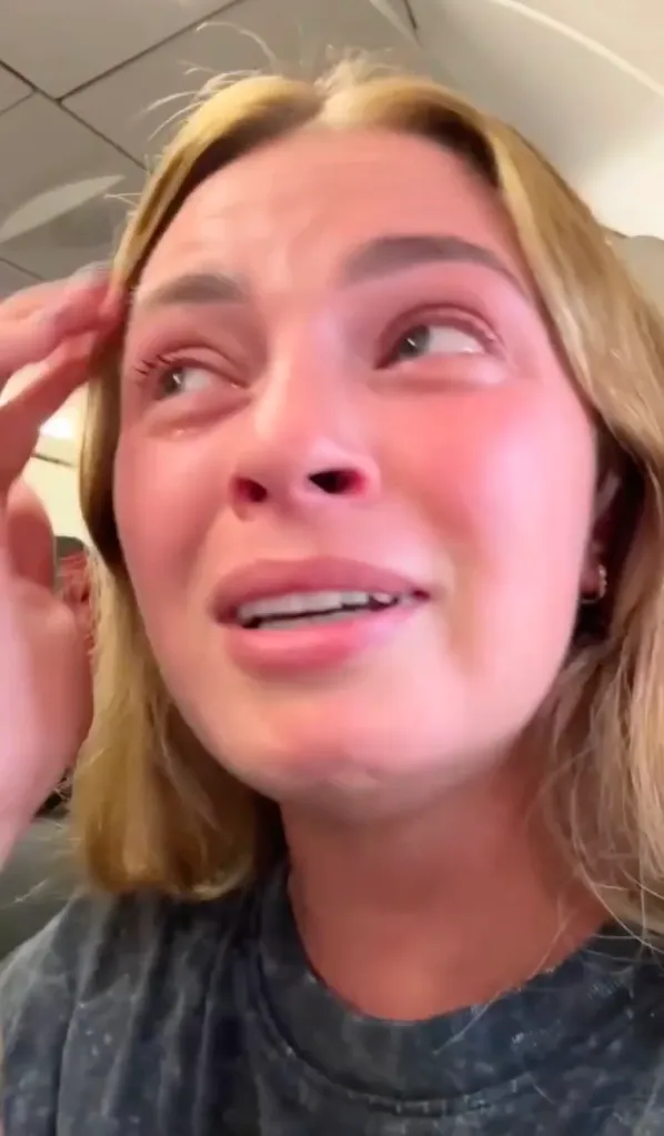 A distressed passenger with tears in her eyes and red-flushed cheeks on a turbulent flight.
