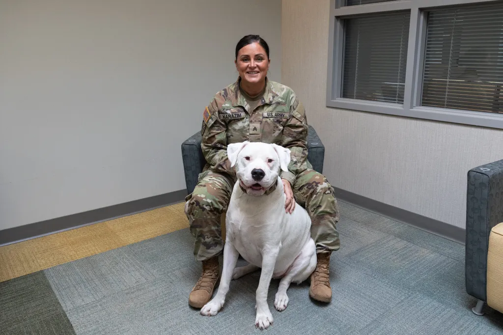 Sgt. Mollie M. Karazim with Axel, a unit ministry dog, at Joint Force Headquarters.