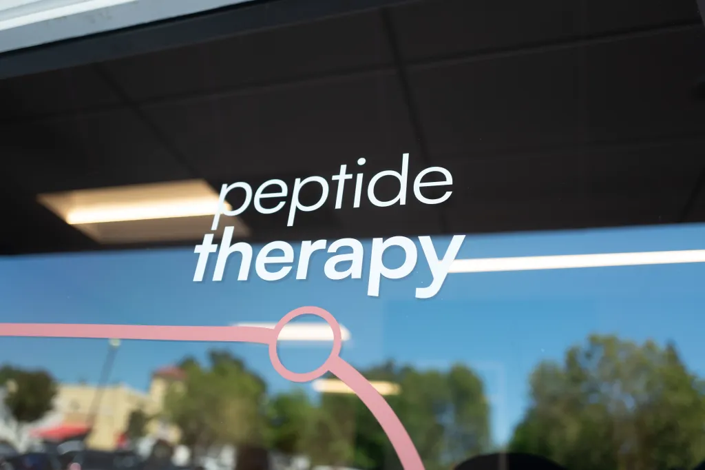 Signage for Peptide Therapy treatments on glass.