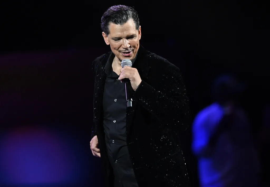 El DeBarge singing into a microphone on stage.