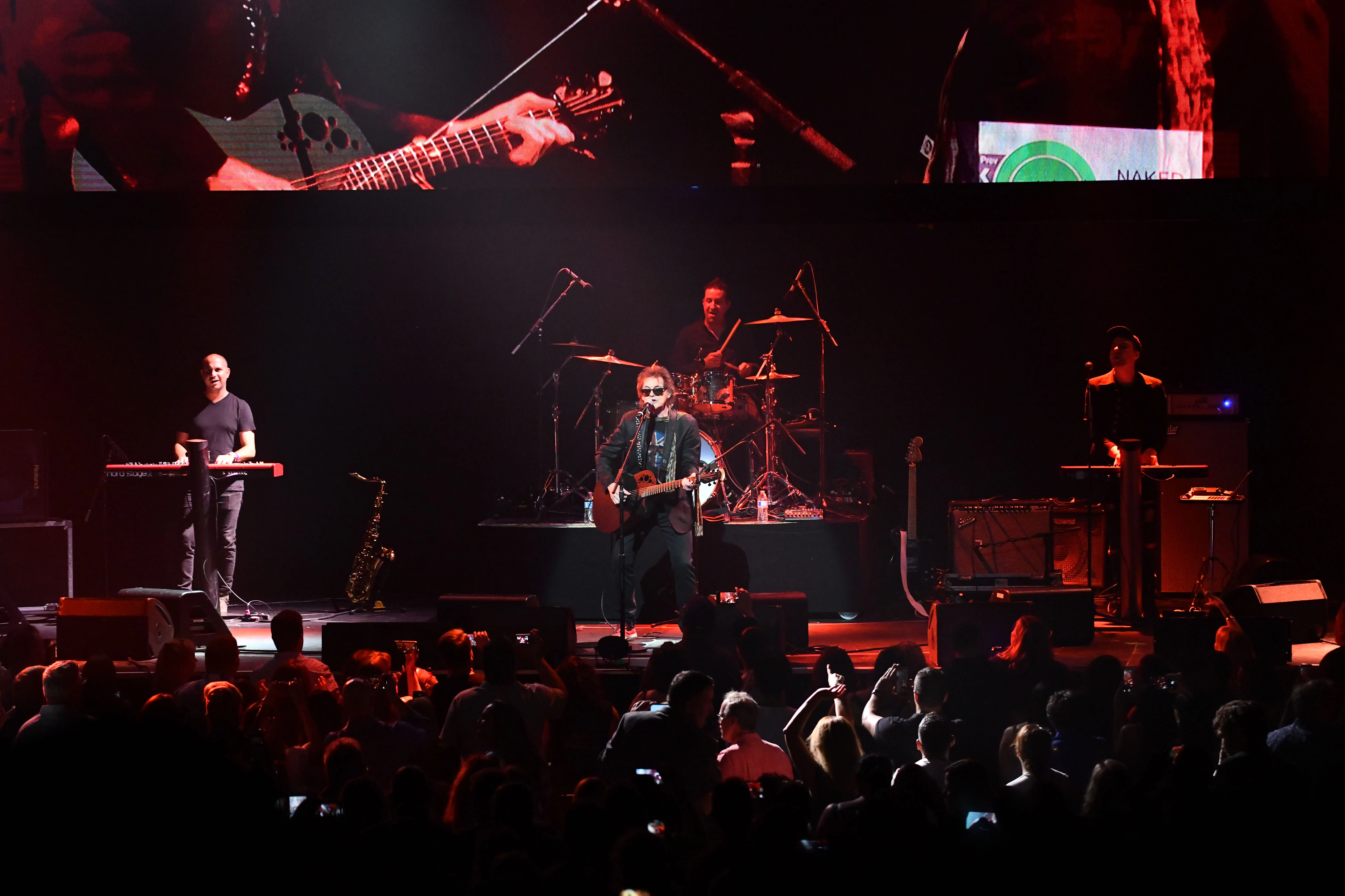 Singer Pete Byrne of Naked Eyes performs on stage with other musicians in front of a crowd.