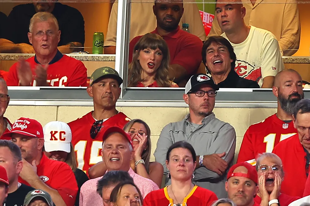 Singer Taylor Swift and actor Tom Cruise watching a game from a stadium box.