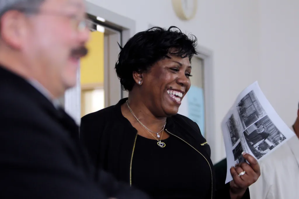 Gwendolyn Westbrook, director of the United Council of Human Services, smiles while holding a document.
