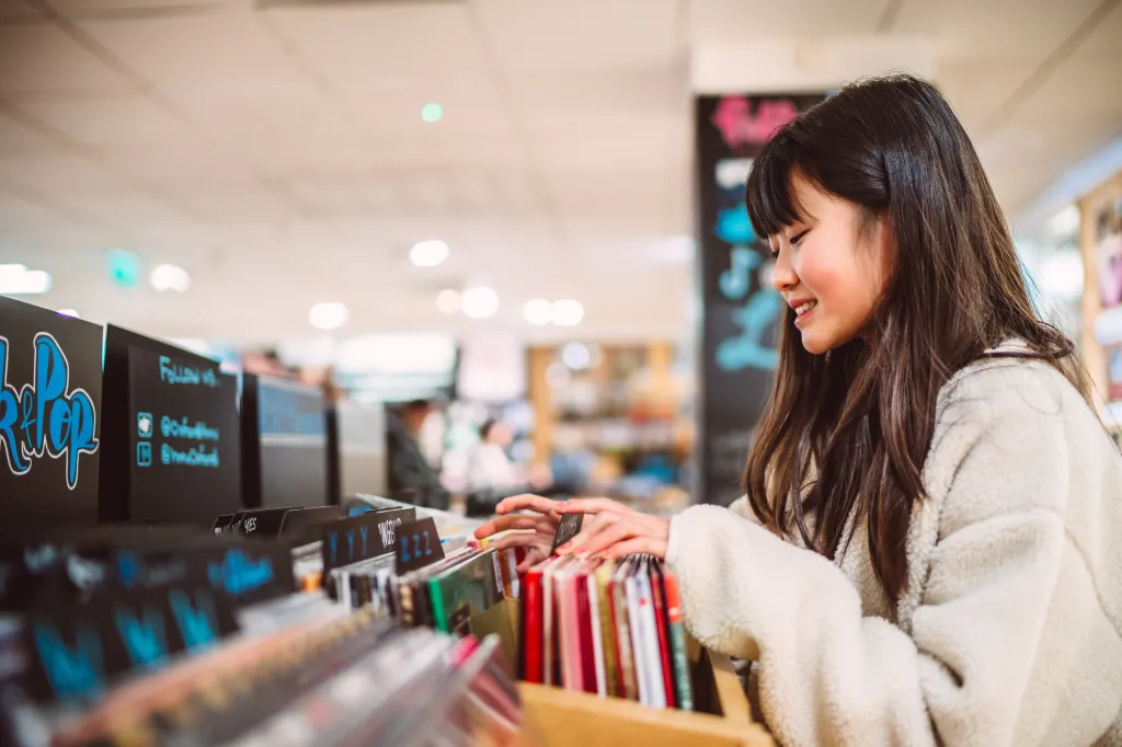 Smiling teenage girl browsing vinyl records in a store.