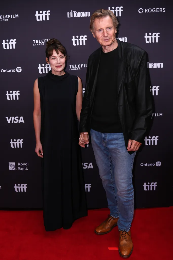 Stella Stocker and Liam Neeson holding hands at the 2026 Toronto International Film Festival premiere of 'Evil Genius.'