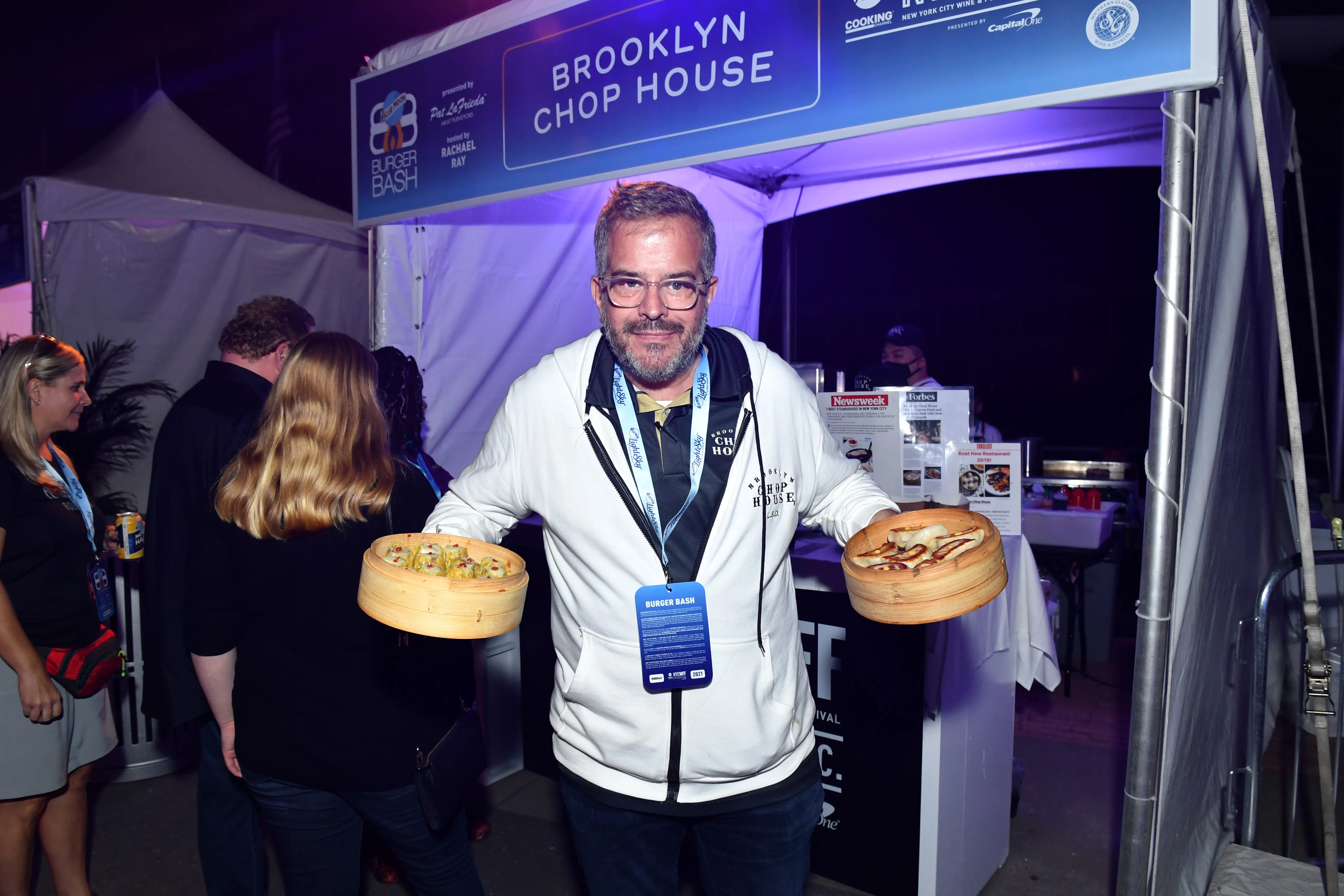 Stratis Morfogen of Brooklyn Chop House holding two bamboo steamers of food at the NYC Wine & Food Festival.