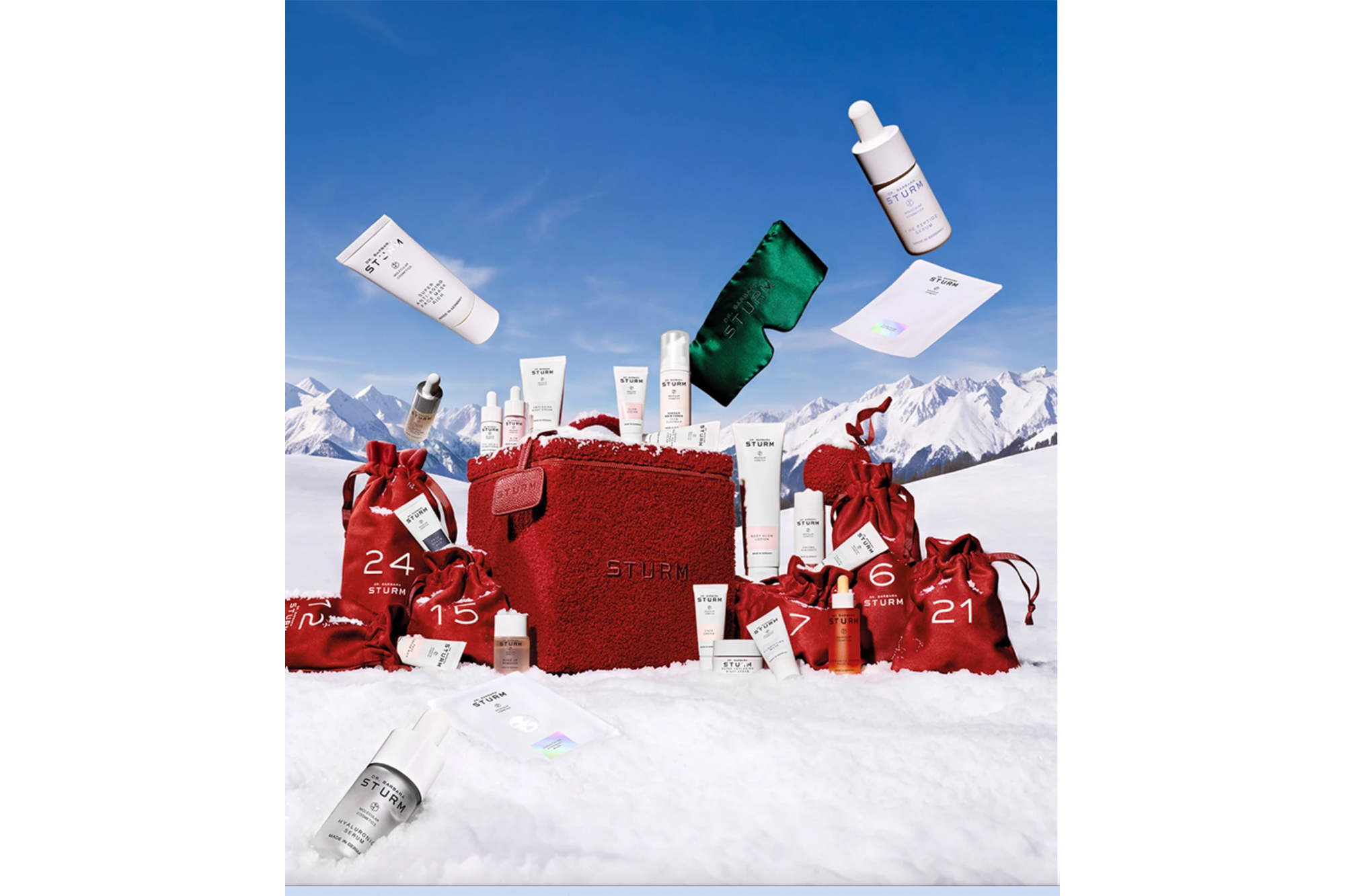 Dr. Barbara Sturm Advent Calendar 2022 with skincare products in red bags and a red cosmetic case, set against a snowy mountain backdrop.