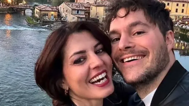 Lorena Isceri and her ex-partner, Federico Vella, smiling together with a river and buildings in the background.