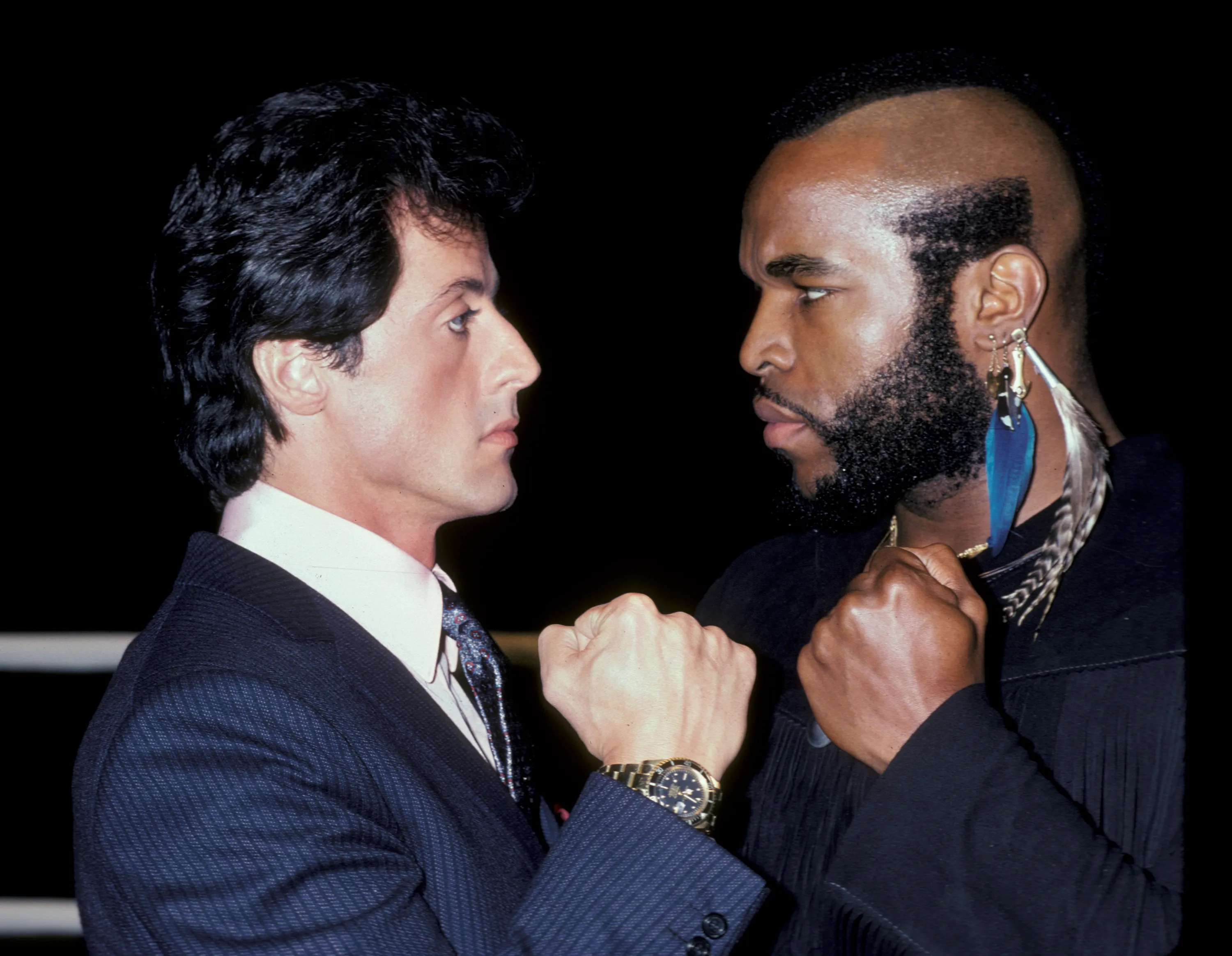 Sylvester Stallone and Mr. T face each other with fists raised at a press conference for 