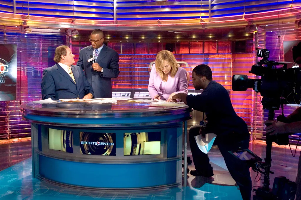Chris Berman talks with Stuart Scott while Linda Cohn reviews a highlight at the SportsCenter desk.