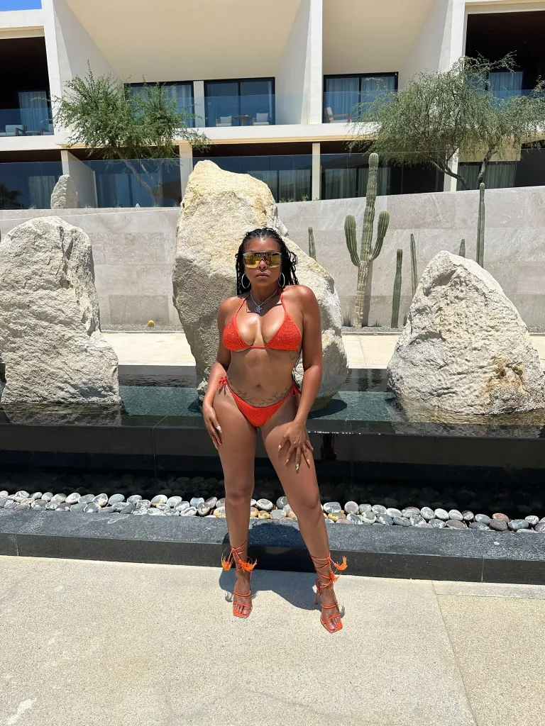 Taraji P. Henson in an orange bikini and heels posing in front of a hotel.