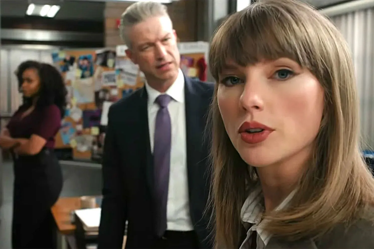 Taylor Swift as an investigator looks at the camera, with two colleagues in the background.