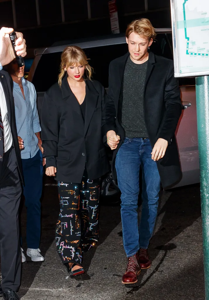Taylor Swift and Joe Alwyn hold hands, walking together.