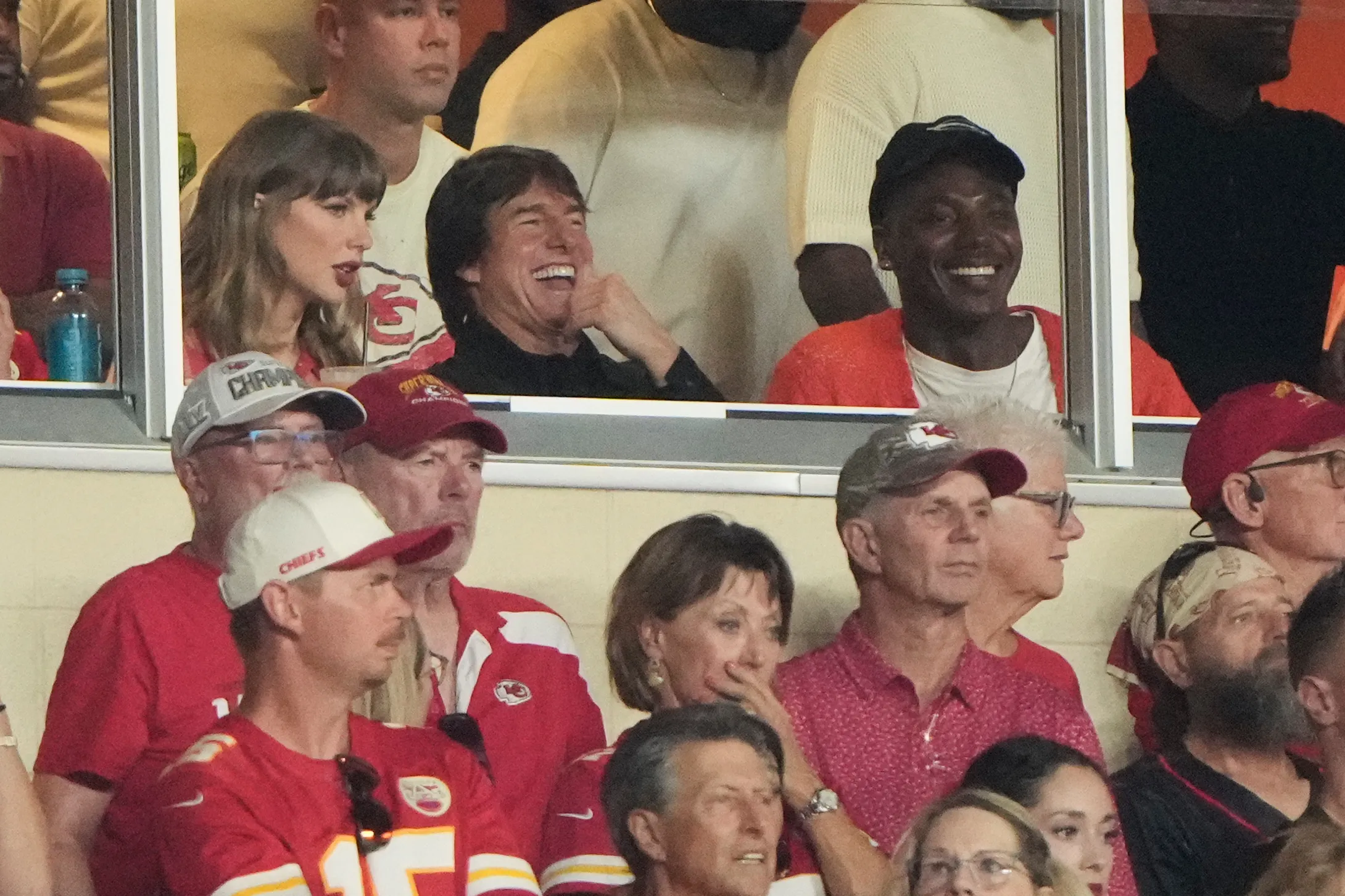 Taylor Swift and Tom Cruise watching an NFL game with other spectators.