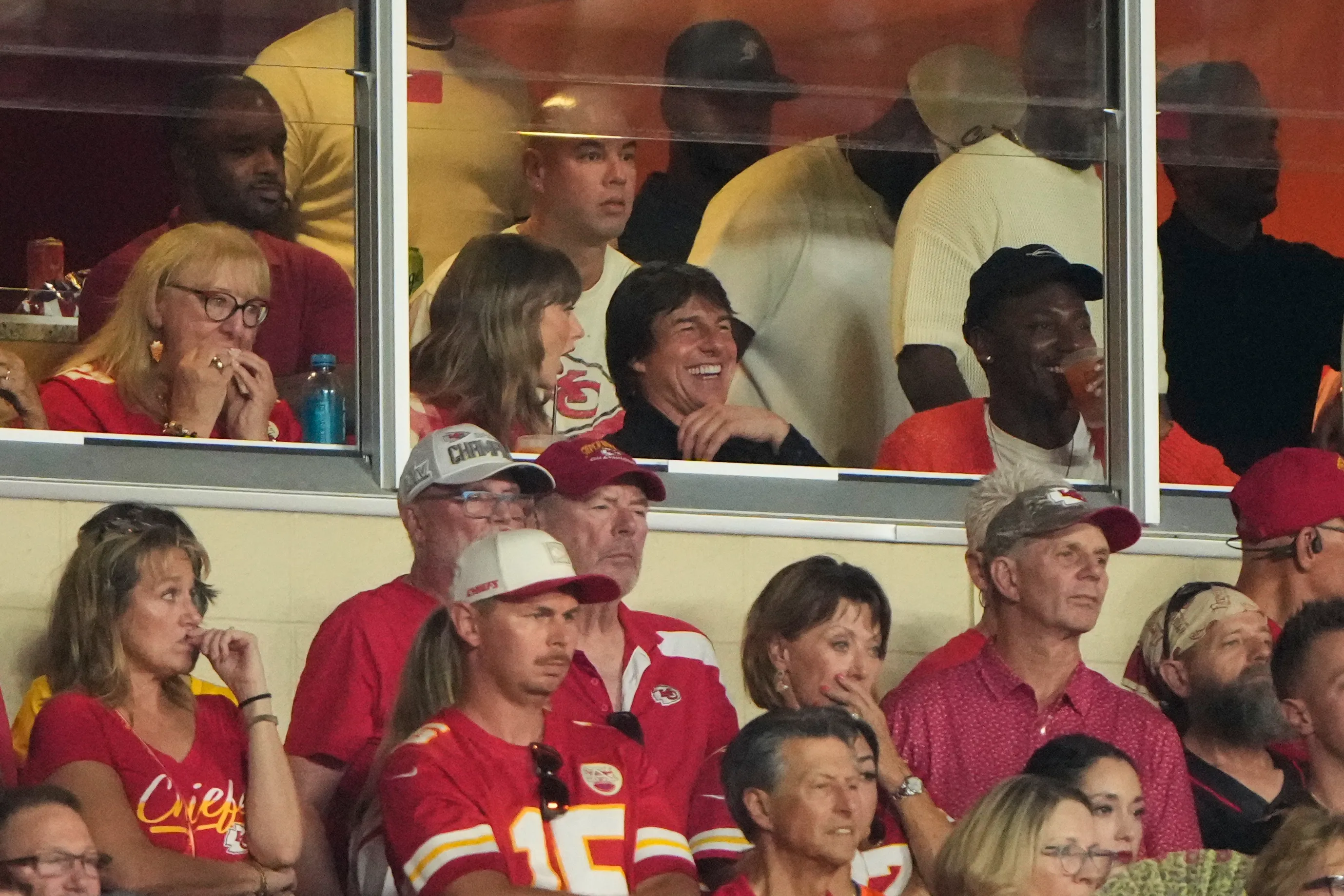 Taylor Swift and Tom Cruise sit together while watching an NFL game.