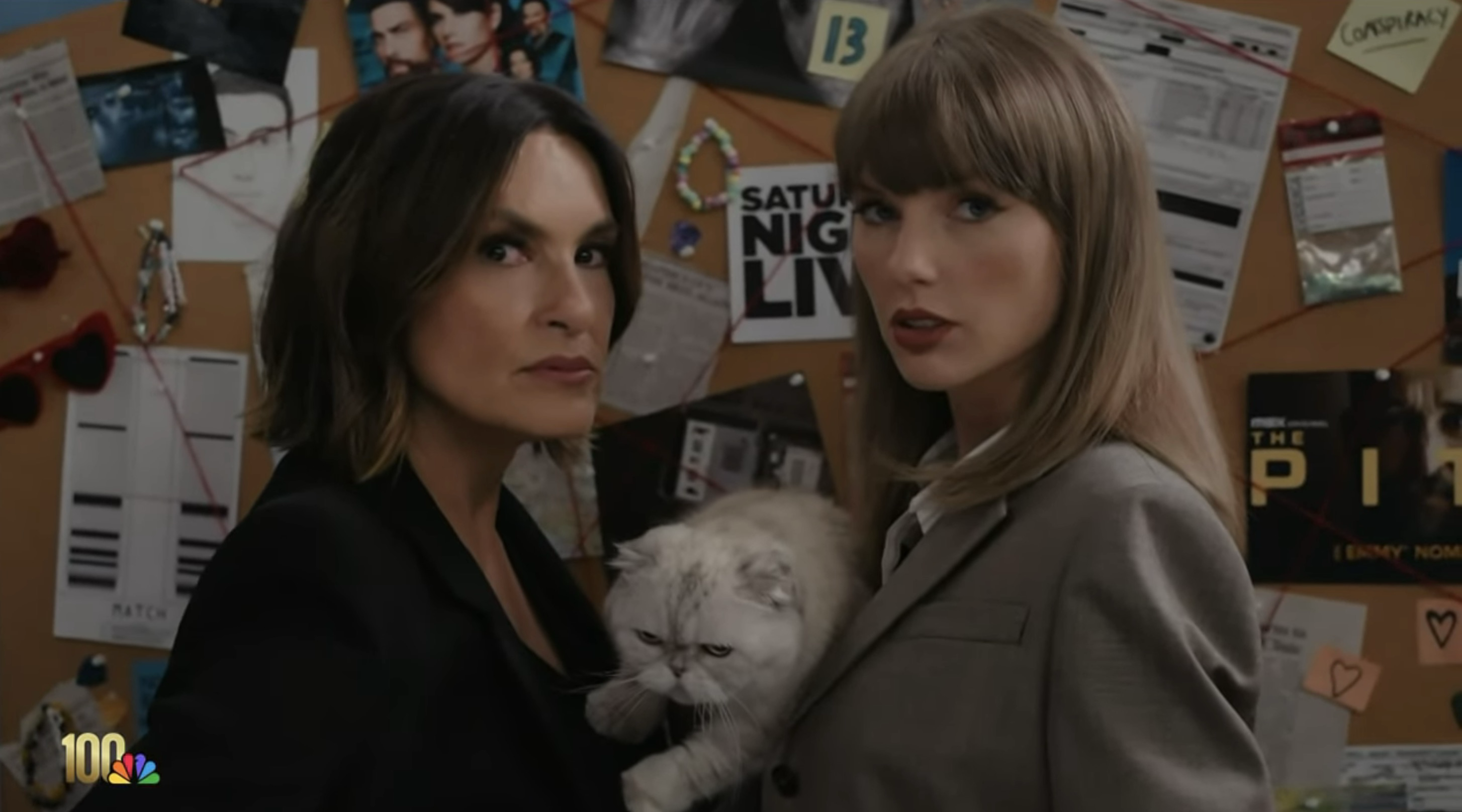 Taylor Swift and Mariska Hargitay holding a cat in front of a bulletin board.