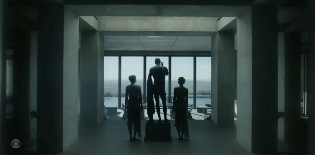 Three figures standing in a room with a large window looking out onto a landscape.