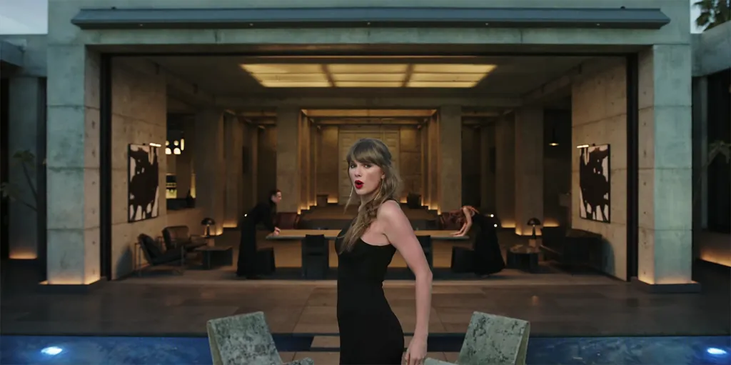 Taylor Swift in a black dress in a modern house.