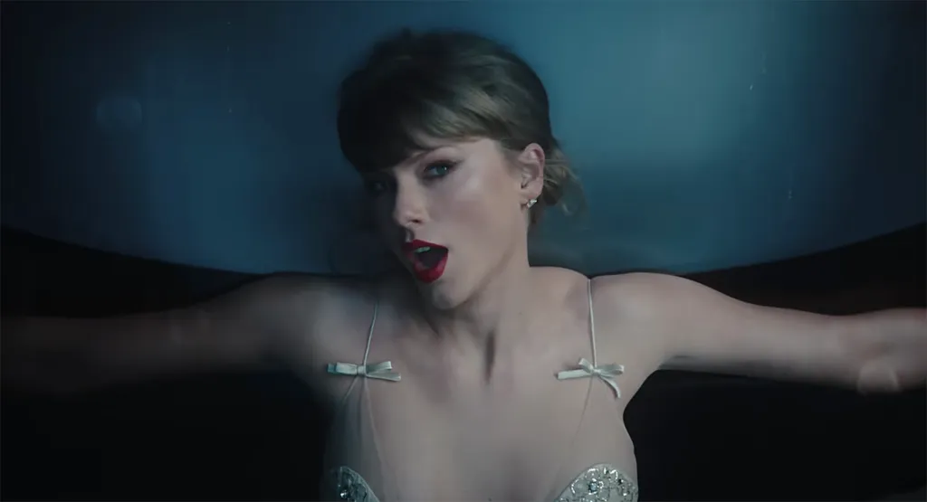 Taylor Swift with red lipstick lying in dark water from her