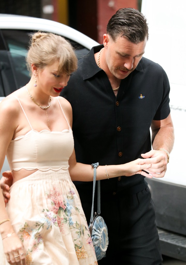 Taylor Swift in a floral dress and Travis Kelce in a black shirt, holding hands as they arrive at Electric Lady Studios.