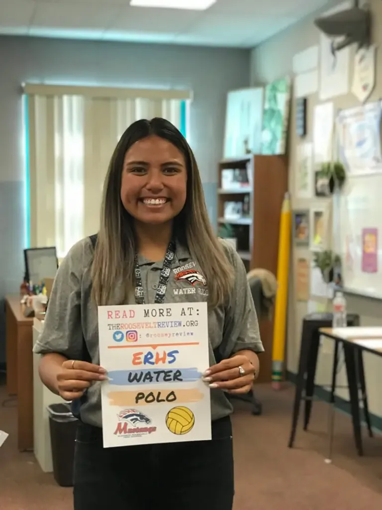 Teacher Amanda Leigh Quinonez holding a sign promoting ERHS Water Polo and The Roosevelt Review.