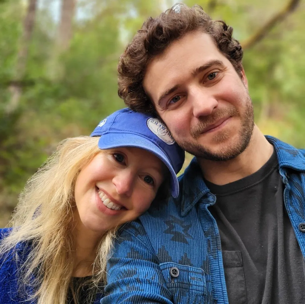 Elizabeth Holmes leans her head on the shoulder of a man in a blue plaid shirt.