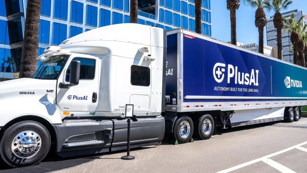 A semi-truck with a trailer branded with PlusAI and Nvidia logos parked on an asphalt lot.