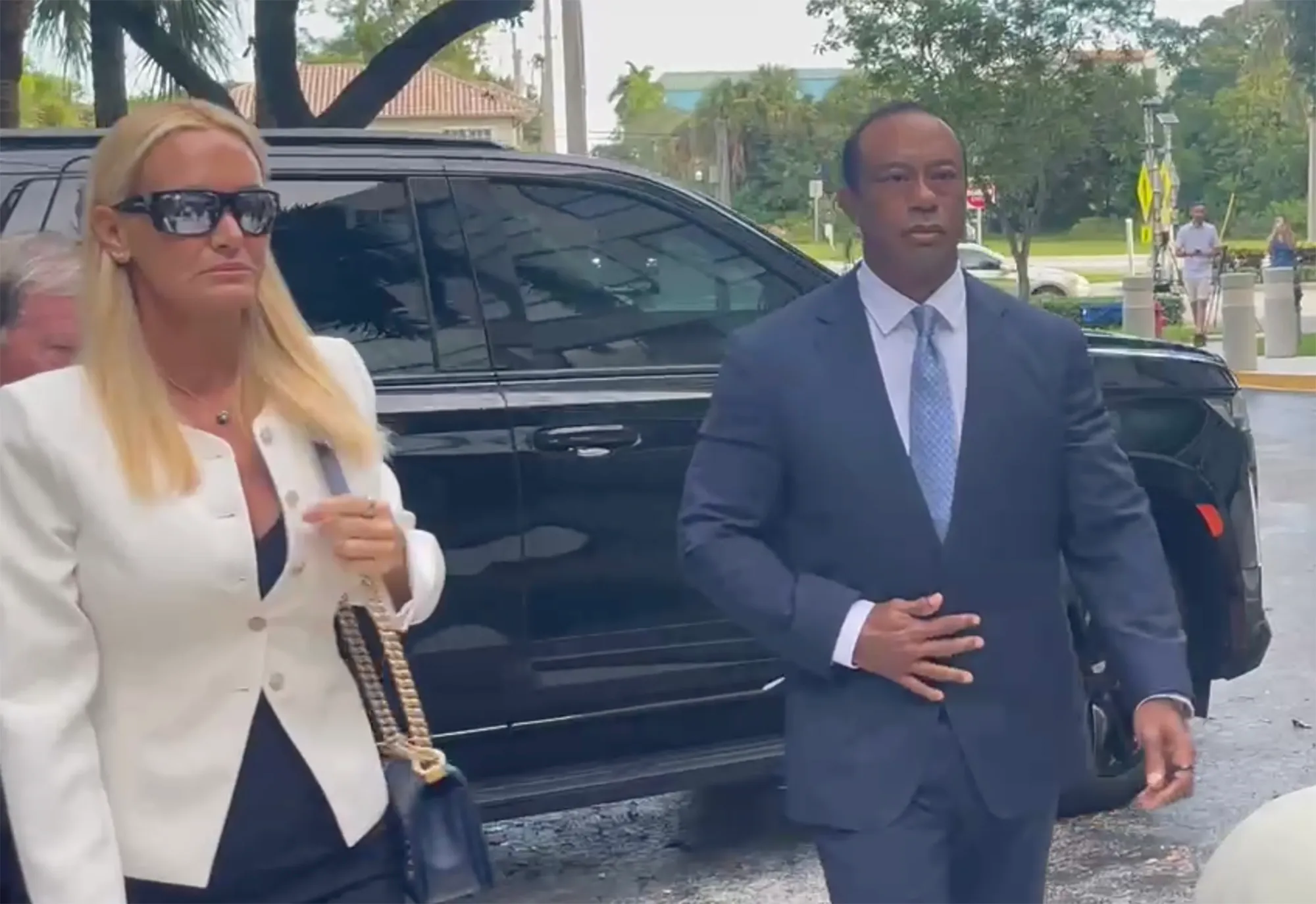 Tiger Woods and Vanessa Trump walking next to a black SUV.