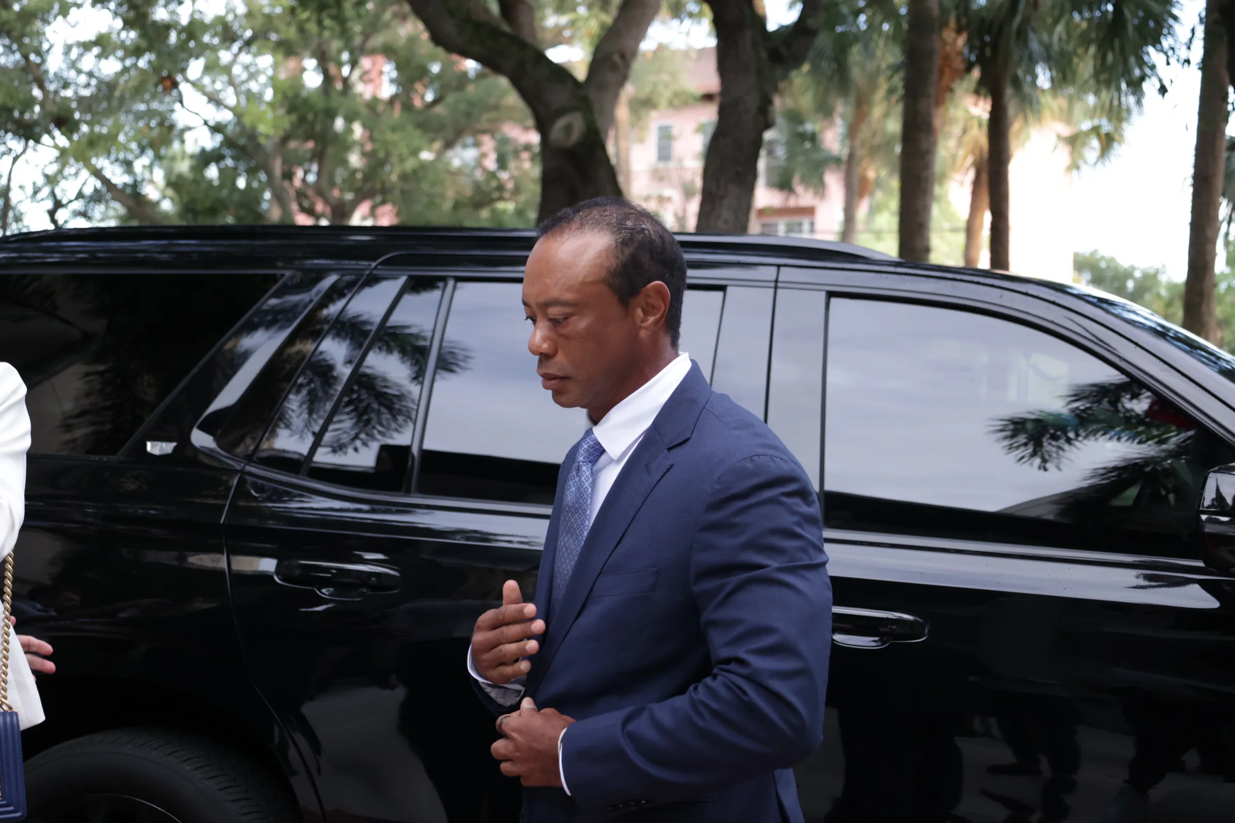 Tiger Woods exiting a black vehicle.