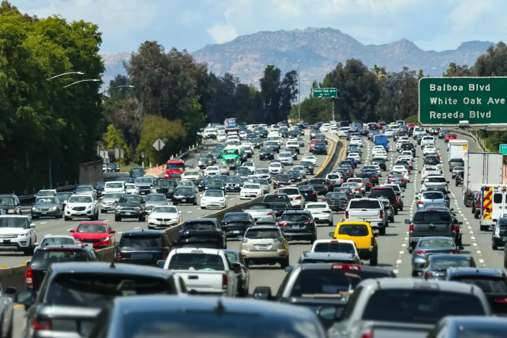 Traffic jam on a Los Angeles freeway with multiple cars and a street sign visible.