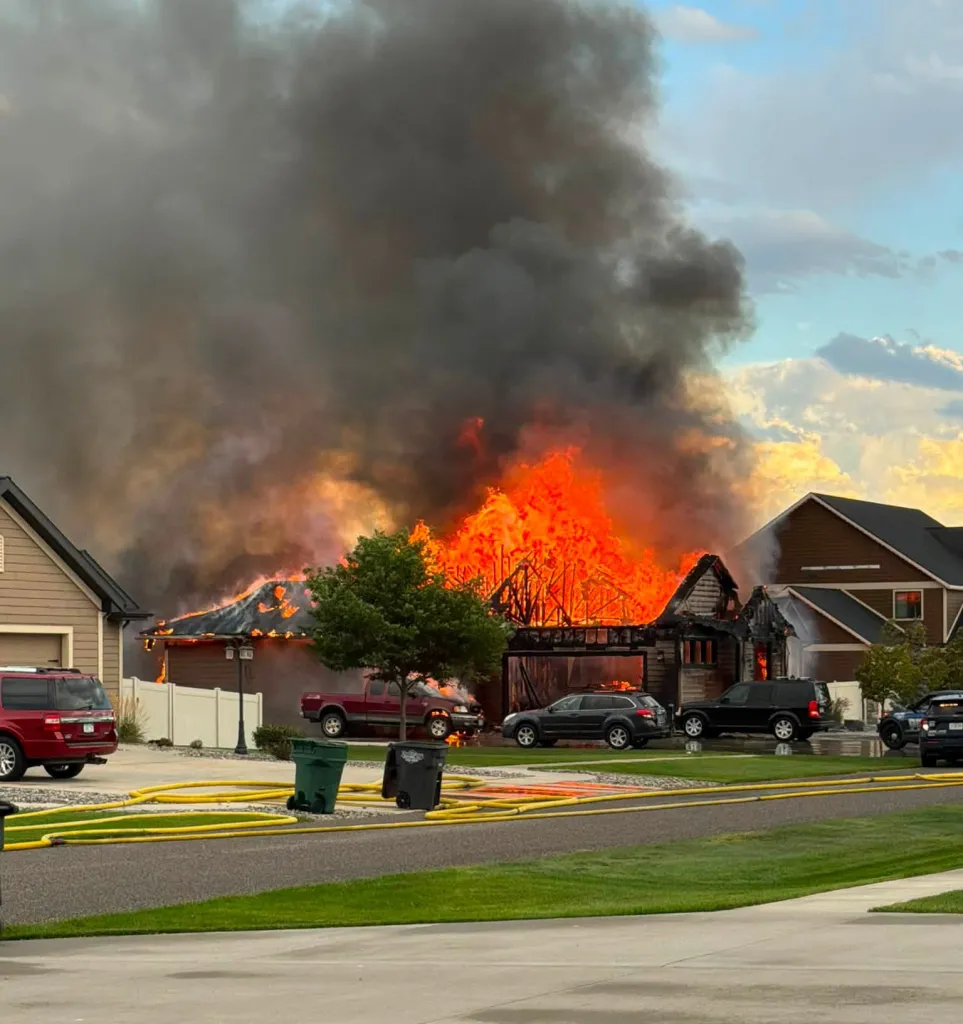 A house fully engulfed in flames with thick smoke billowing from the roof.