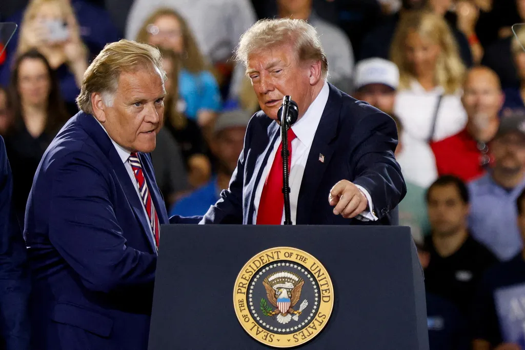 U.S. President Donald Trump stands with former U.S. Representative Mike Rogers as Trump delivers remarks on the economy.