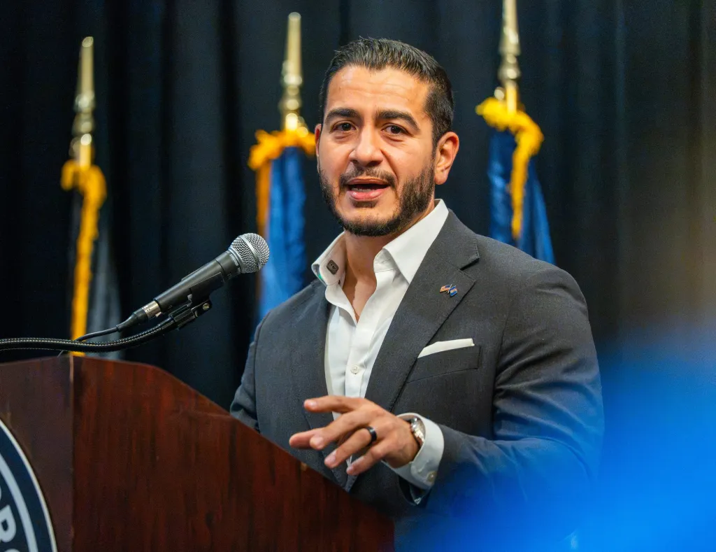 U.S. Senate candidate Abdul El-Sayed speaking to UAW workers at a podium.