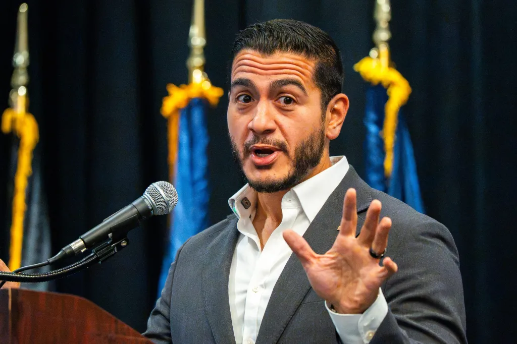Abdul El-Sayed speaking at a podium with a microphone.