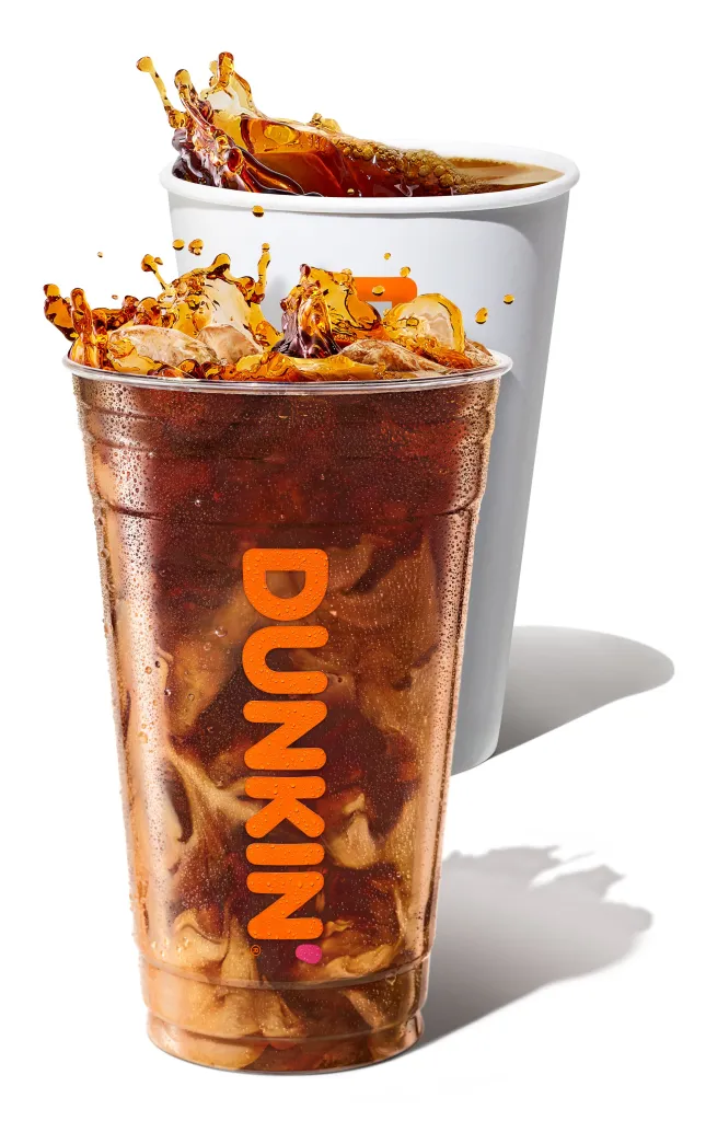 An iced Dunkin' coffee and a hot Dunkin' coffee, both with coffee splashing out.