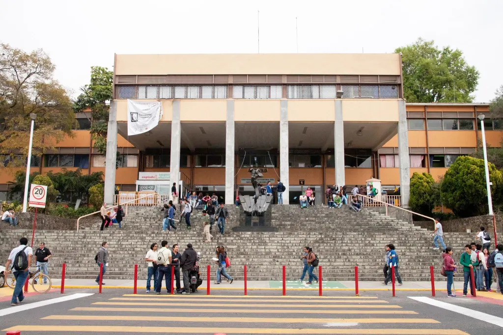 The building of the Universidad Autónoma del Estado de Morelos, with many students on the stairs and in front.