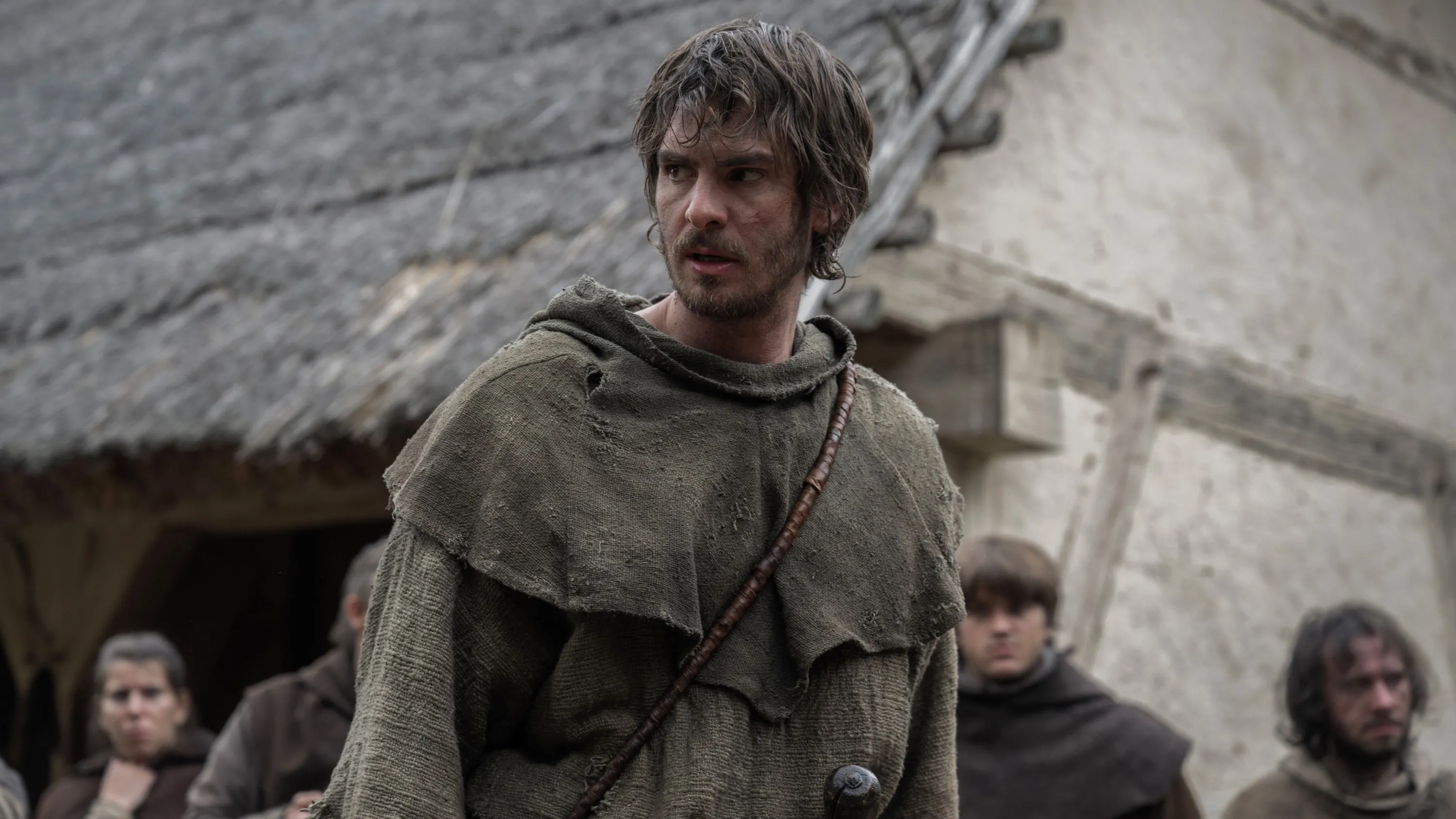 Andrew Garfield as a commoner with dirty hair and a tattered robe, looking to his right.