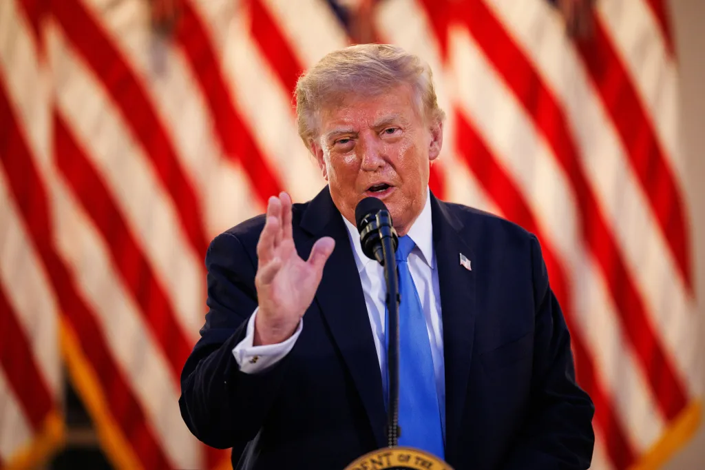 Donald Trump speaking at a podium with American flags in the background.